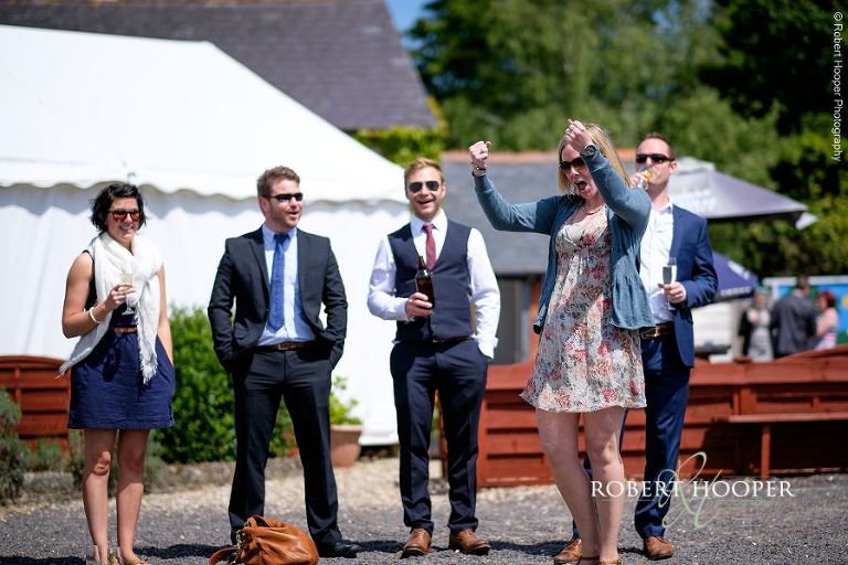Wedding guest punches the air as she wins the bean bag toss game at summer wedding reception at The Three Tuns Bransgore, Dorset