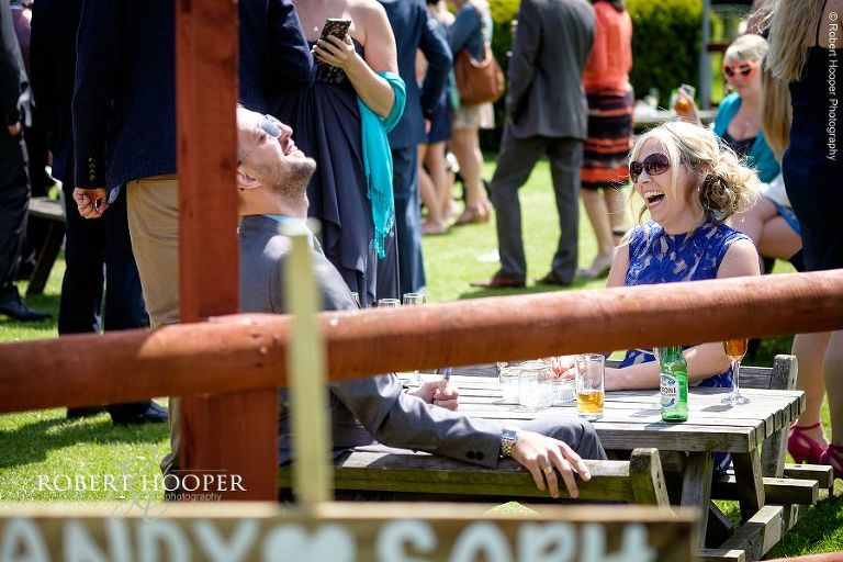 Wedding guests enjoying the sunshine and a beer laughing together in the garden at wedding reception at The Three Tuns Bransgore, Dorset