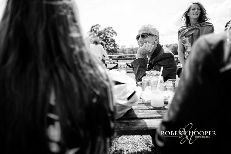 Wedding guest seated at picnic table with other guests for summer wedding reception at The Three Tuns Bransgore, Dorset