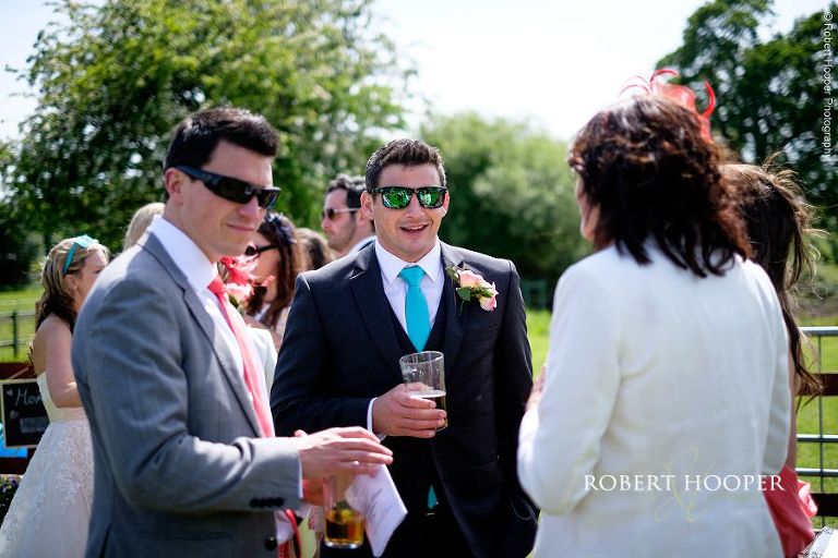 Groom wearing sunglasses, chatting to wedding guests at outdoor garden reception in The Three Tuns Bransgore, Dorset