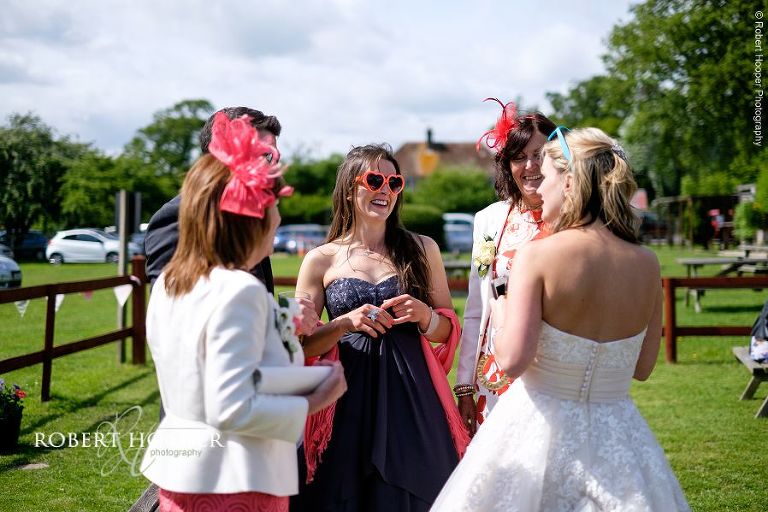 Bride and bridesmaids chat to wedding guests at summer wedding reception in the garden of The Three Tuns Bransgore, Dorset