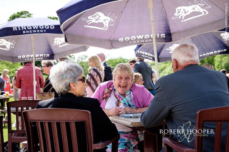 Wedding guests sitting under umbrellas in beer garden at wedding reception at The Three Tuns Bransgore Dorset