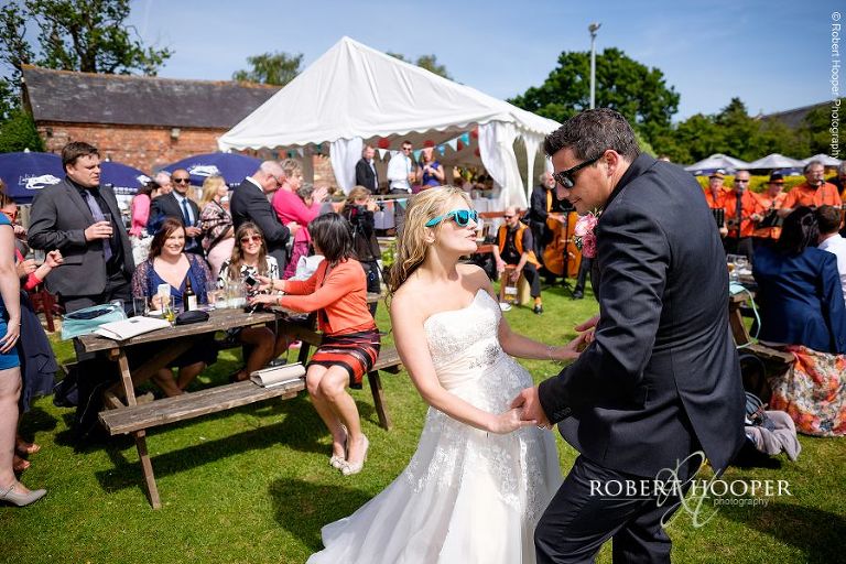 Bride and groom dancing together in sunglasses to the music of the string wedding band at their wedding celebration in the gardens of The Three Tuns Bransgore Dorset