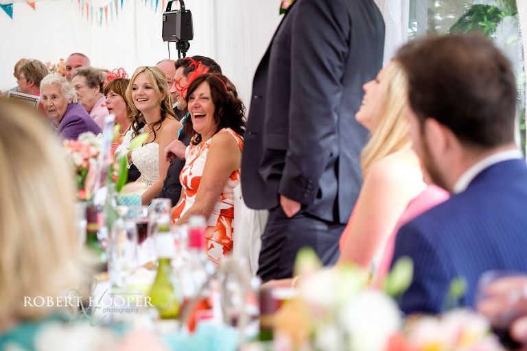 Wedding guests enjoying best man's speech at wedding breakfast in the marquee of The Three Tuns Bransgore Dorset