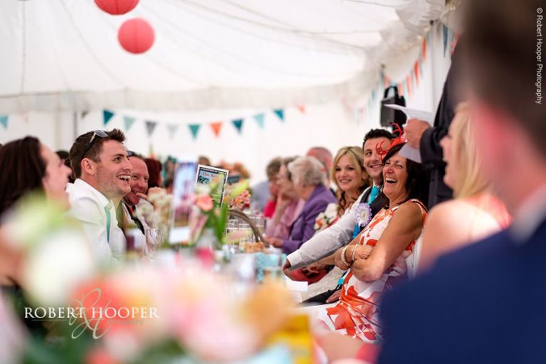Wedding guests enjoying best man's speech at wedding breakfast in the marquee of The Three Tuns Bransgore Dorset