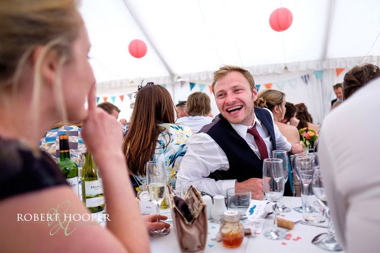 Wedding guests seated at picnic style tables at wedding reception in the marquee at The Three Tuns Bransgore Dorset