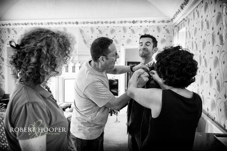 Mother of the bride attaching groomsmen button hole before wedding ceremony at Eastwell Manor Ashford Kent