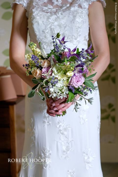 Bride holding her beautiful bouquet of wild flowers ready to leave room for wedding ceremony at Eastwell Manor Ashford Kent