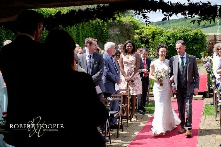 Bride walks down the isle at outdoor wedding ceremony held at Eastwell Manor Ashford Kent