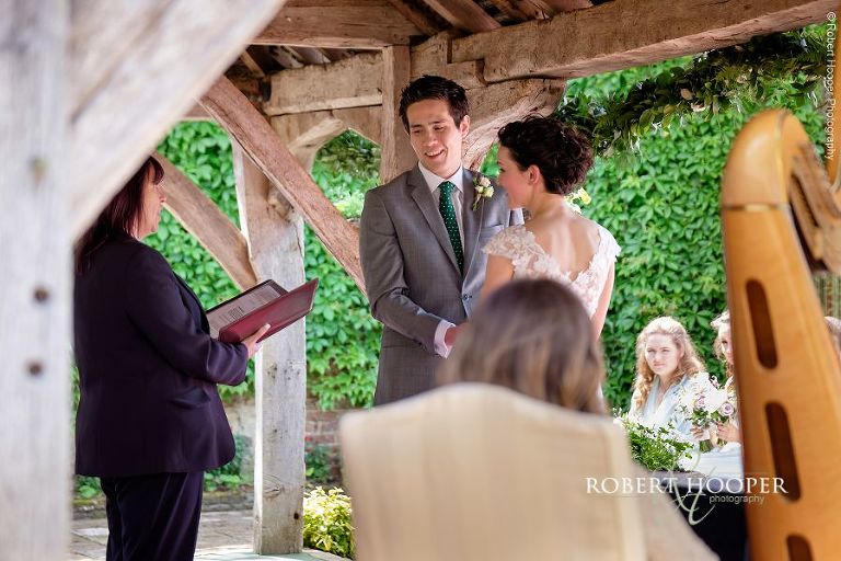 Bride and groom say their marriage vows under the pergola during outdoor ceremony at Eastwell Manor Ashford Kent