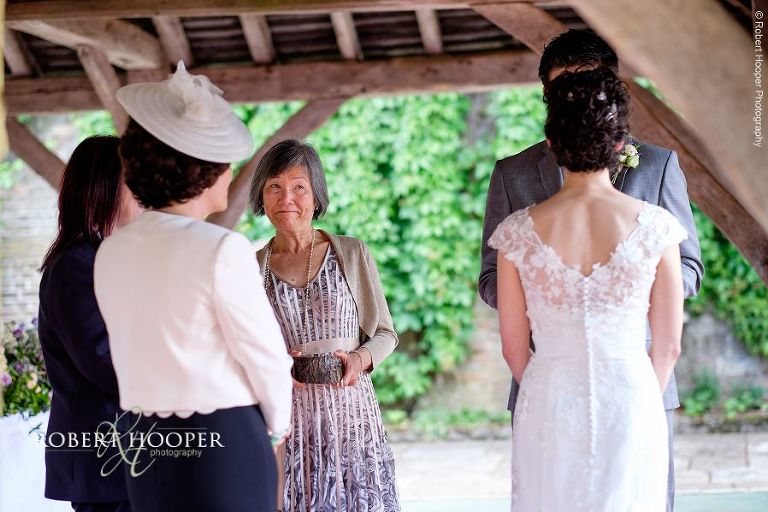Mother of the groom holding the rings but sheds an emotional tear during outdoor civil wedding ceremony at Bride and groom say their vows at Eastwell Manor Ashford Kent