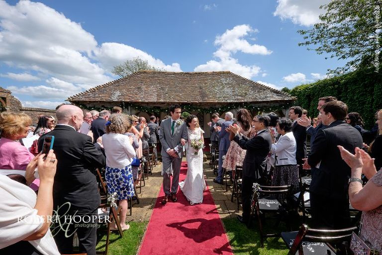 Newlyweds walk back down the isle as man and wife following outdoor civil wedding ceremony held in the gardens at Eastwell Manor Ashford Kent