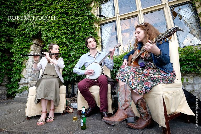 Band consisting of guitarist, banjo player, flute player playing for guests at wedding drinks reception at Eastwell Manor Ashford Kent