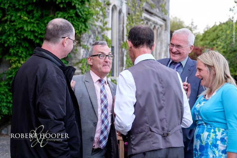 Wedding guests chatting to groom's father at drinks reception at at Eastwell Manor Ashford Kent