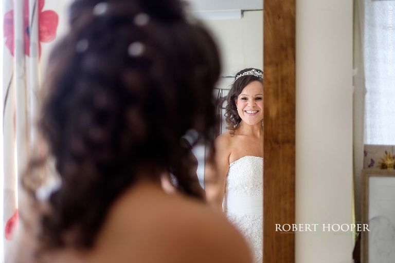 Bride checking her hair in the mirror before putting on veil and leaving for her wedding ceremony at St Peter & St Paul's Church, Chaldon and Brewer Street Farmhouse in Bletchingly Surrey