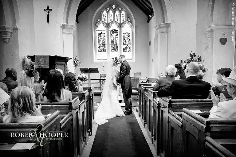 Bride and groom kiss when they are pronounced husband and wife at their wedding at St. Peter & St. Paul's church, Chaldon in Surrey
