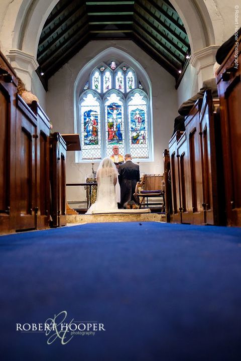 Bride and groom kneeling at the alter for their blessing during their marriage at St. Peter's & St. Paul's church in Chaldon