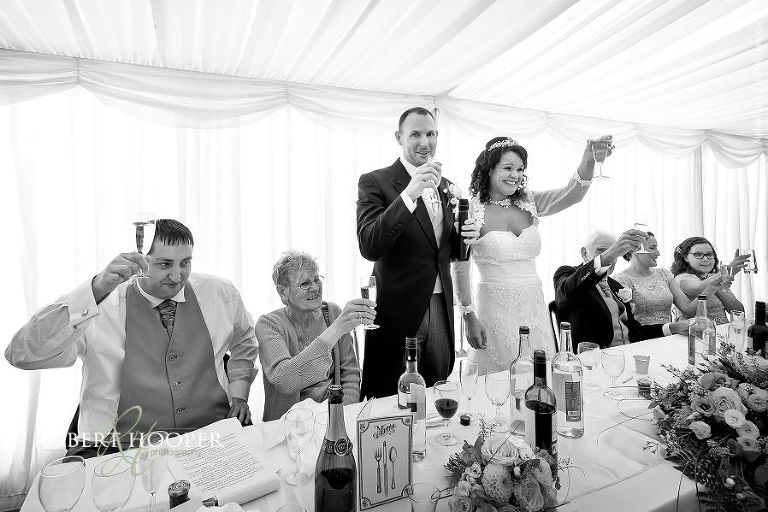 Guests toast the new Mr and Mrs at their wedding breakfast celebration in Marquee at Brewer Street Farmhouse in Surrey