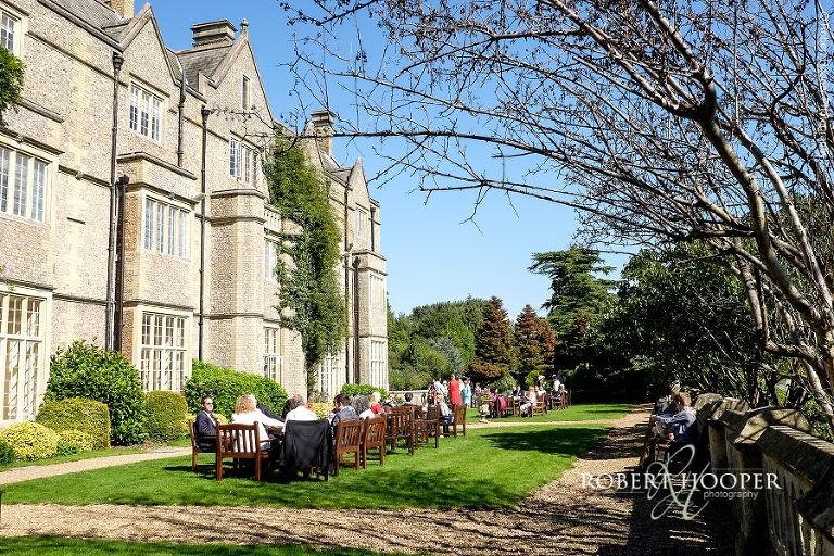 Wedding guests seated outside in the gardens at Horsley Towers Surrey for champagne reception