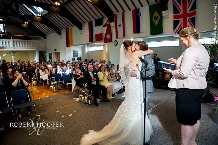 Guests clapping as bride and groom kiss when they are pronounced man and wife at Bookham Baptist Church Surrey