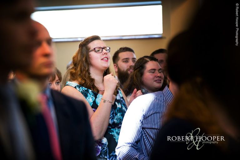Wedding guests singing hymns at wedding service at Bookham Baptist Church Surrey