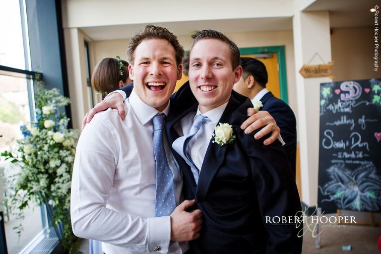 Groom gets a hug from his best man after his wedding ceremony at Bookham Baptist Church Surrey