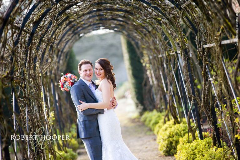 Newlyweds under the pergola in the gardens at Loseley Park Surrey on their wedding day