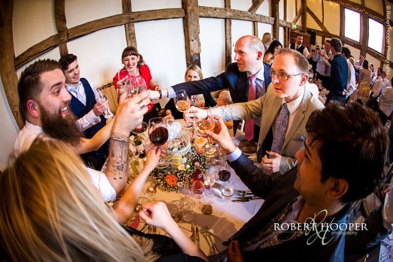 Wedding guests toasting the "happy couple" at wedding breakfast celebration held in The Tithe Barn at Loseley Park Surrey