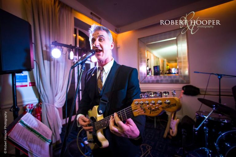 Musician singing and playing guitar for wedding guests at reception at Chilston Park in Kent