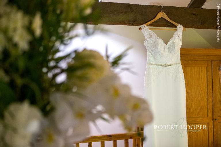 Wedding dress hanging in the cottage on wedding day at Oaks Farm Shirley Surrey