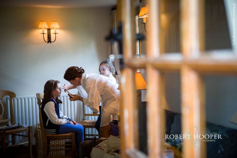 Bride putting a touch of make-up on flower girls at wedding at Oaks Farm Barn Shirley Surrey