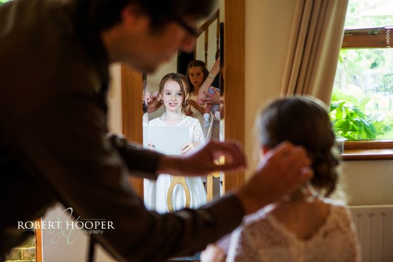 Flower girl having her hair pinned on wedding day in the cottage at Oaks Farm Barn Shirley Surrey
