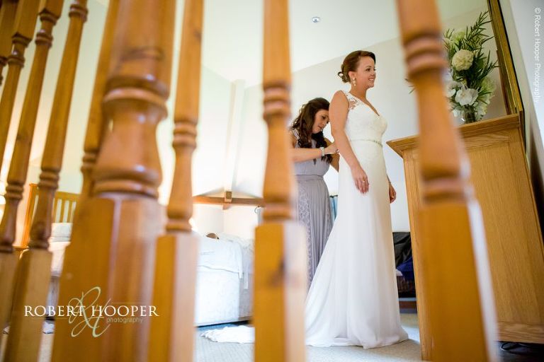 Bride putting on wedding dress on wedding day in the cottage at Oaks Farm Barn Shirley Surrey