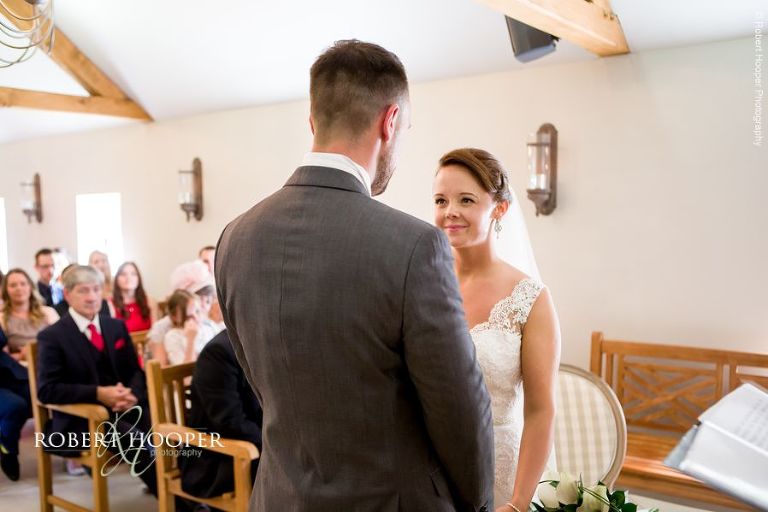 Bride smiles lovingly at her groom during civil wedding ceremony at Oaks Farm Shirley Surrey