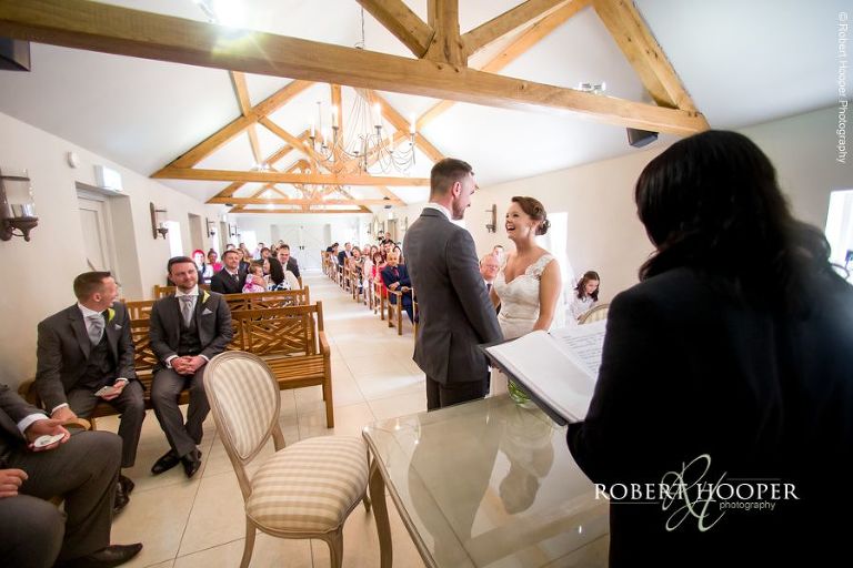 Bride and groom share laughter during their civil wedding ceremony at Oaks Farm Barn Croydon Surrey