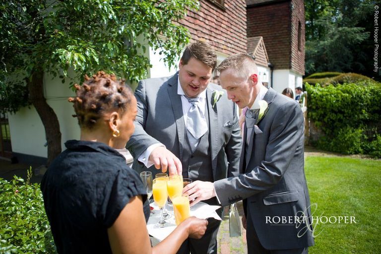 Groomsmen being served a bucks fizz by venue staff at Oaks Farm Barn Shirley Surrey