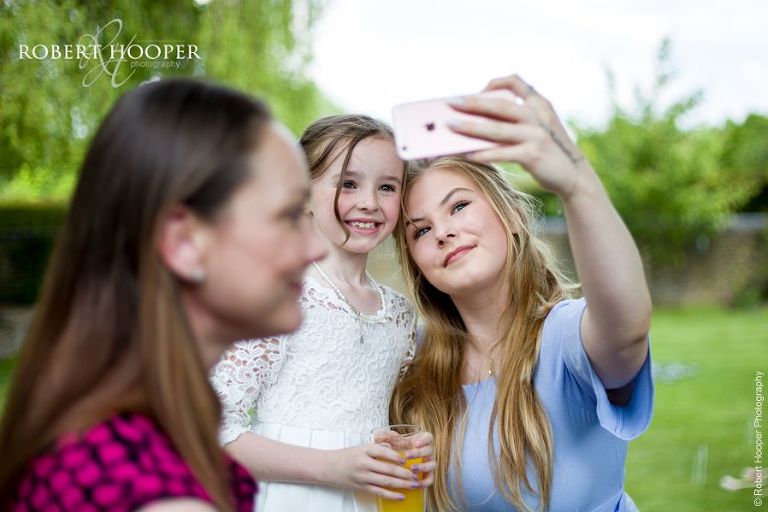 Flower girl and younger wedding guest take a selfie with their iPhone on wedding day at Oaks Farm Barn Shirley Croydon