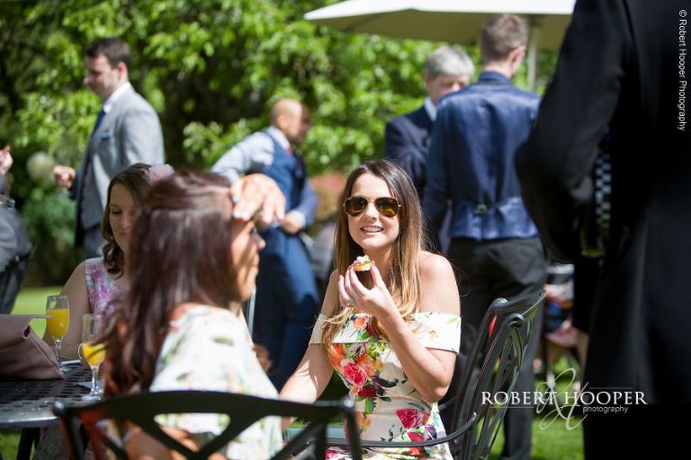 Wedding guests enjoying canapes in the sun on the lawn at Oaks Farm Barn Croydon Surrey