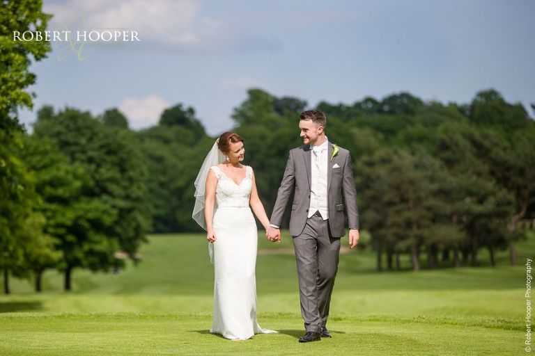 Bride and groom holding hands walking in the landscape on their wedding day in Surrey
