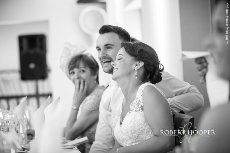 Bride and groom laughing at speech by father of the bride at their wedding at Oaks Farm Barn Shirley Surrey