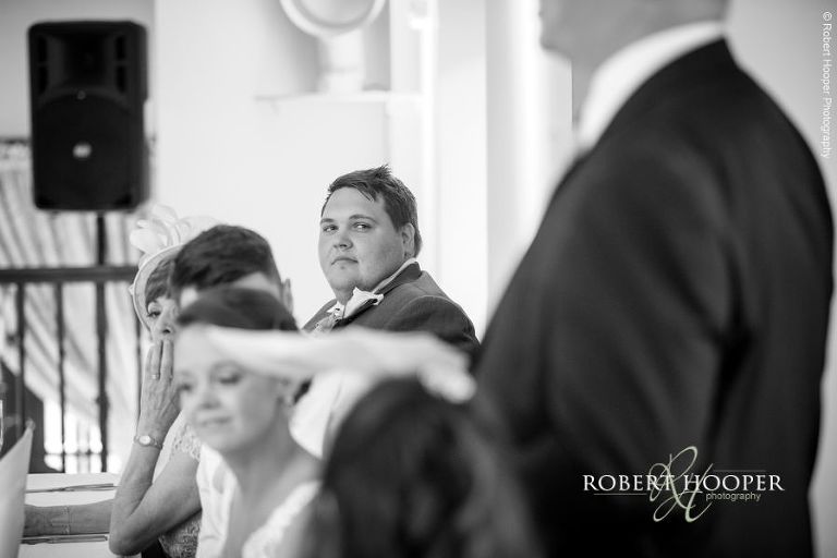 Best man listening to speech by father of the bride at wedding breakfast at Oaks Farm Barn Surrey