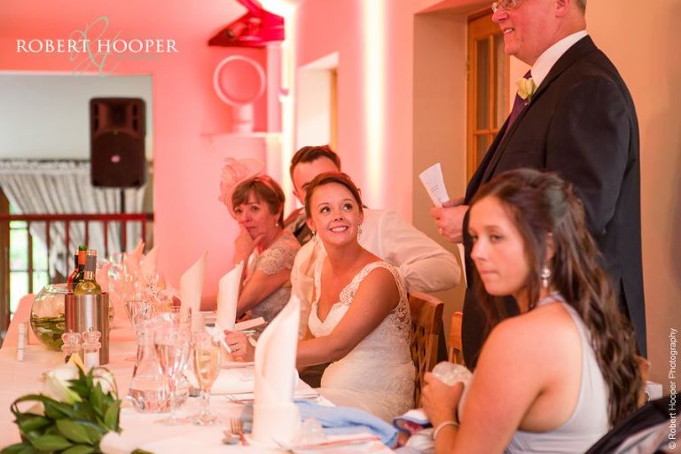 Bride smiling at speech by dad at wedding breakfast at Oaks Farm Barn Shirley Surrey