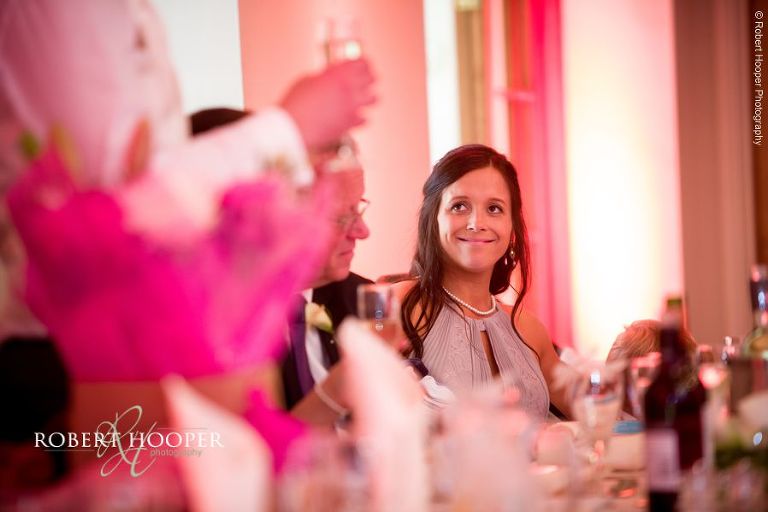 Bridesmaid smiling at the groom during his speech from top table at wedding breakfast at Oaks Farm Barn Croydon Surrey
