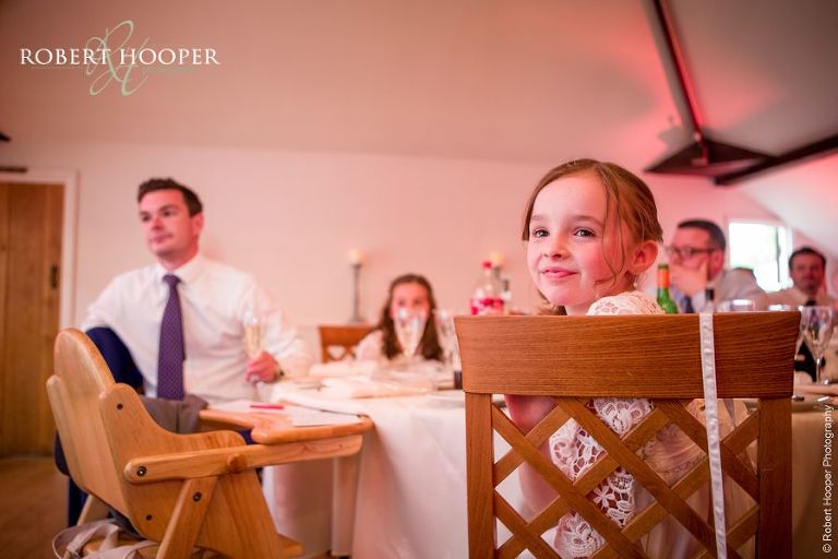 Flower girl listening attentively during speeches by her mum and dad during wedding breakfast at Oaks Farm Barn Surrey