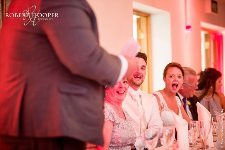 Bride laughing at best man's speech during wedding breakfast at Oaks Farm Barn Shirley Surrey