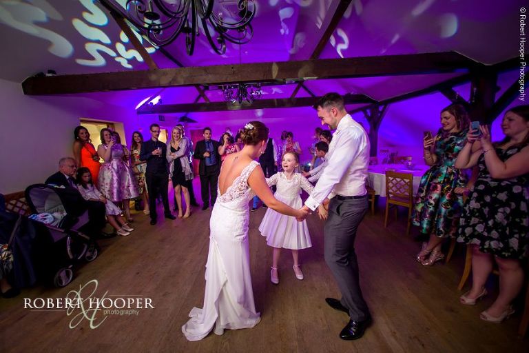 Newlyweds dance with the flower girl after their first dance at Oaks Farm Barn Croydon Surrey