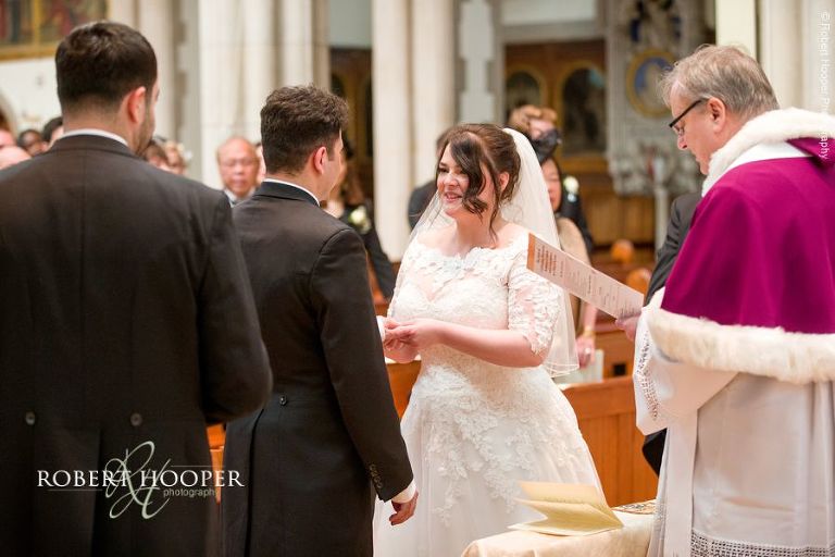 Bride and groom exchange wedding rings during the marriage service at Sacred Heart Church Wimbledon London