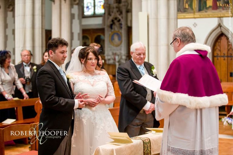 Bride and groom at the alter during wedding service at Sacred Heart Church Wimbledon London