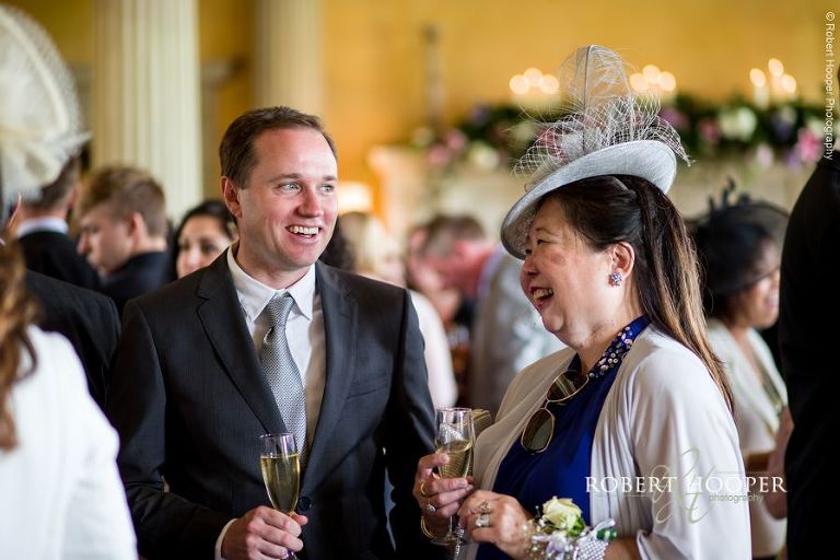 Wedding guests enjoying champagne during reception on wedding day at Hampton Court House Surrey