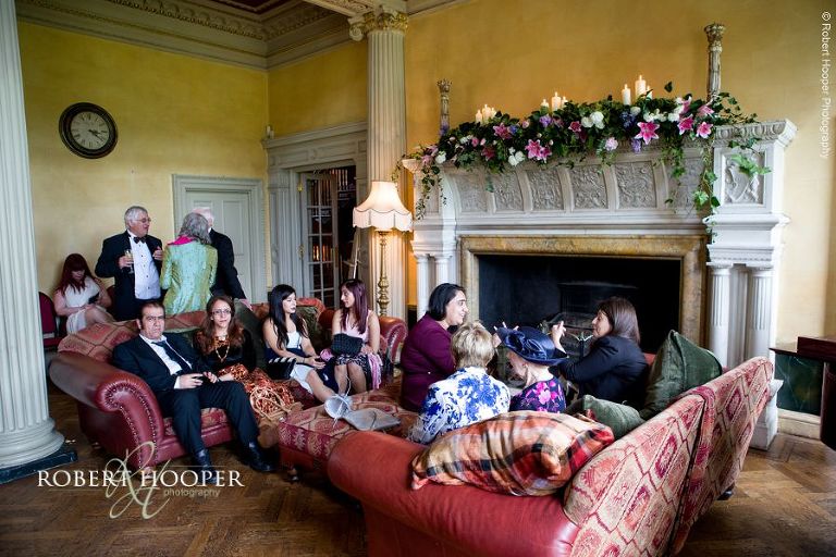 Wedding guests seated around fireplace at Hampton Court House Surrey